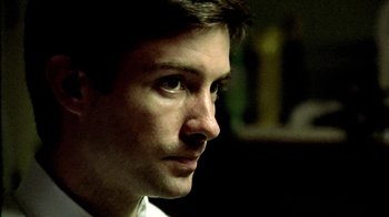 Movie still from “Primer” (2004), directed by Shane Carruth – A man's face in a dark room; Extreme Close Up shot, Low angle