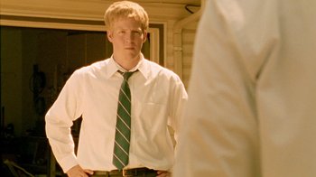 Movie still from “Primer” (2004), directed by Shane Carruth – A man in a white dress shirt and green tie; Medium shot, Low angle