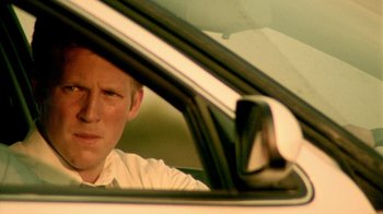 Movie still from “Primer” (2004), directed by Shane Carruth – A man sitting in the driver's seat of a car; Close Up shot, Over the shoulder angle