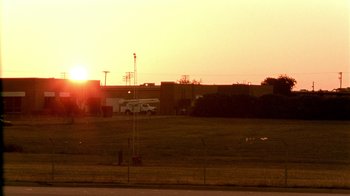Movie still from “Primer” (2004), directed by Shane Carruth – The sun is setting over a field with a van parked in front of it; Extreme Wide shot, Low angle