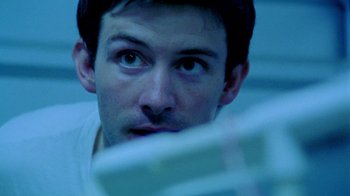Movie still from “Primer” (2004), directed by Shane Carruth – A person looking at a computer screen; Close Up shot, Low angle