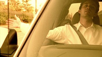 Movie still from “Primer” (2004), directed by Shane Carruth – A man sitting in the driver's seat of a car; Close Up shot, Low angle