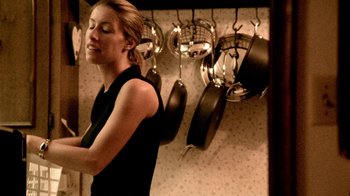 Movie still from “Primer” (2004), directed by Shane Carruth – A woman standing in front of pots and pans hanging on the wall; Medium shot, Low angle
