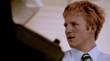 Movie still from “Primer” (2004), directed by Shane Carruth – A man with red hair wearing a white shirt and a green tie; Close Up shot, Low angle