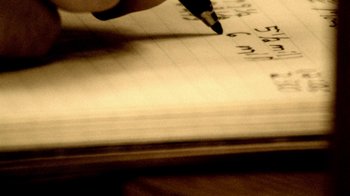 Movie still from “Primer” (2004), directed by Shane Carruth – A person writing in a notebook with a pen; Extreme Close Up shot, Overhead angle