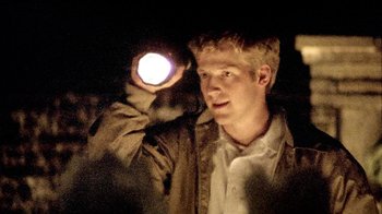 Movie still from “Primer” (2004), directed by Shane Carruth – A young man holding a flashlight in the dark; Close Up shot, Low angle