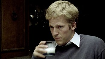 Movie still from “Primer” (2004), directed by Shane Carruth – A man holding a glass in his hand; Close Up shot, Over the shoulder angle