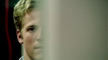 Movie still from “Primer” (2004), directed by Shane Carruth – A young man is looking into the camera; Extreme Close Up shot, Over the shoulder angle
