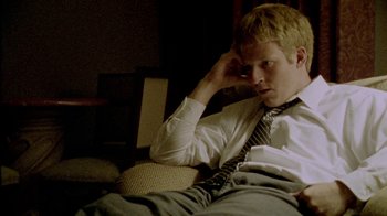 Movie still from “Primer” (2004), directed by Shane Carruth – A man sitting on a couch with his hand on his head; Medium shot, High angle