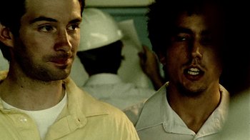 Movie still from “Primer” (2004), directed by Shane Carruth – A couple of men standing next to each other; Close Up shot, Over the shoulder angle