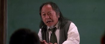 Movie still from “Prince of Darkness” (1987), directed by John Carpenter – An older man with long black hair wearing a tie; Close Up shot, Low angle