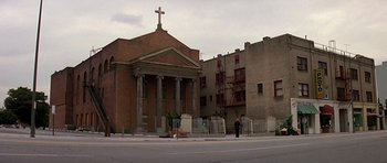 Movie still from “Prince of Darkness” (1987), directed by John Carpenter – A person standing in front of a building with a cross on top of it; Extreme Wide shot, Low angle
