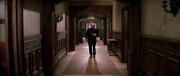 Movie still from “Prince of Darkness” (1987), directed by John Carpenter – A man walking down a hall way in a suit; Wide shot, Low angle
