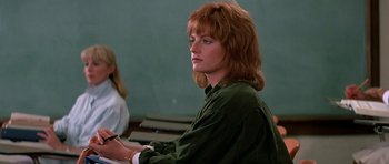 Movie still from “Prince of Darkness” (1987), directed by John Carpenter – A woman sitting in front of a green wall in a classroom; Close Up shot, Over the shoulder angle