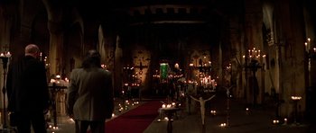 Movie still from “Prince of Darkness” (1987), directed by John Carpenter – Candles are lit in a church during a service; Wide shot, High angle