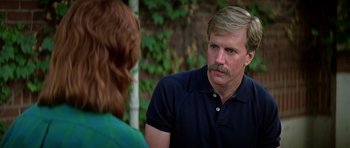 Movie still from “Prince of Darkness” (1987), directed by John Carpenter – A man with a mustache talking to a woman in front of a brick wall; Close Up shot, Over the shoulder angle