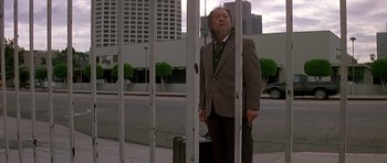 Movie still from “Prince of Darkness” (1987), directed by John Carpenter – An older man standing on the side of the street; Wide shot, Low angle