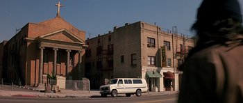 Movie still from “Prince of Darkness” (1987), directed by John Carpenter – A van parked on the side of the road in front of an apartment building; Extreme Wide shot, Low angle