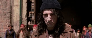 Movie still from “Prince of Darkness” (1987), directed by John Carpenter – A man with long black hair wearing a black hat; Close Up shot, High angle