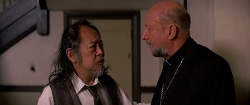 Movie still from “Prince of Darkness” (1987), directed by John Carpenter – Two men are talking to each other in a room; Close Up shot, Low angle