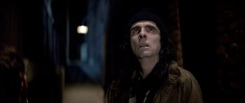 Movie still from “Prince of Darkness” (1987), directed by John Carpenter – A man in a hat and jacket looking at the camera; Close Up shot, Low angle