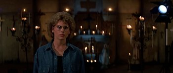Movie still from “Prince of Darkness” (1987), directed by John Carpenter – A man with glasses standing in front of a cross; Close Up shot, Low angle