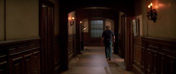 Movie still from “Prince of Darkness” (1987), directed by John Carpenter – A man walking down a hall way in a house; Wide shot, High angle