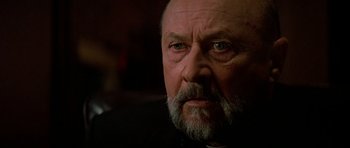 Movie still from “Prince of Darkness” (1987), directed by John Carpenter – An older man with a beard and a mustache; Close Up shot, Low angle