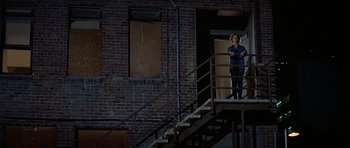 Movie still from “Prince of Darkness” (1987), directed by John Carpenter – A woman standing on the stairs of a building; Wide shot, High angle