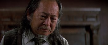 Movie still from “Prince of Darkness” (1987), directed by John Carpenter – An older man with long hair and a beard; Close Up shot, Low angle