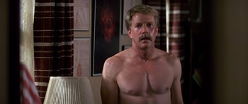 Movie still from “Prince of Darkness” (1987), directed by John Carpenter – A man with a mustache standing in front of a mirror; Medium shot, Low angle