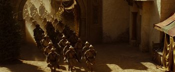 Movie still from “Prince of Persia: The Sands of Time” (2010), directed by Mike Newell – A group of men in medieval garb marching down a street; Wide shot, High angle