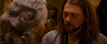 Movie still from “Prince of Persia: The Sands of Time” (2010), directed by Mike Newell – A man with long brown hair and a beard is talking to a woman; Close Up shot, Over the shoulder angle