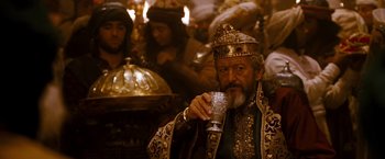 Movie still from “Prince of Persia: The Sands of Time” (2010), directed by Mike Newell – An old man with a beard and a crown is drinking from a cup; Close Up shot, Low angle