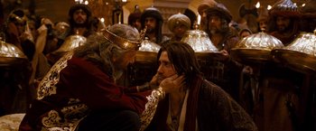 Movie still from “Prince of Persia: The Sands of Time” (2010), directed by Mike Newell – A man with long hair and a crown is touching another man's ear; Close Up shot, Over the shoulder angle