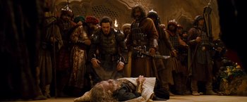 Movie still from “Prince of Persia: The Sands of Time” (2010), directed by Mike Newell – A group of men standing around a man lying on the ground; Wide shot, High angle