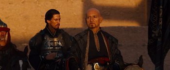 Movie still from “Prince of Persia: The Sands of Time” (2010), directed by Mike Newell – Two men dressed in medieval clothing standing next to each other; Medium shot, Over the shoulder angle