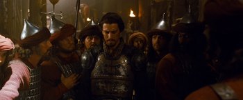 Movie still from “Prince of Persia: The Sands of Time” (2010), directed by Mike Newell – A group of men in medieval armor standing in a room; Medium shot, Over the shoulder angle