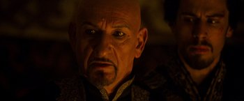 Movie still from “Prince of Persia: The Sands of Time” (2010), directed by Mike Newell – An older man with a bald head and a mustache; Close Up shot, Over the shoulder angle