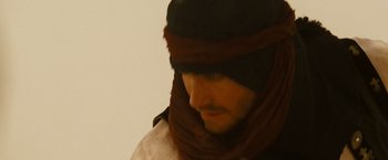 Movie still from “Prince of Persia: The Sands of Time” (2010), directed by Mike Newell – A man wearing a hat and a scarf; Close Up shot, Over the shoulder angle