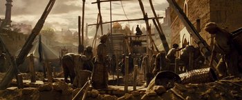 Movie still from “Prince of Persia: The Sands of Time” (2010), directed by Mike Newell – A group of people standing around a building; Wide shot, Low angle