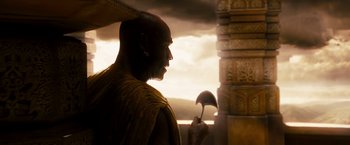 Movie still from “Prince of Persia: The Sands of Time” (2010), directed by Mike Newell – A man with a bald head is looking into the distance; Medium shot, Over the shoulder angle