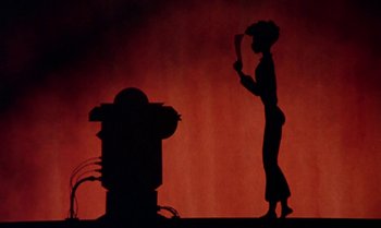 Movie still from “Princes and Princesses” (2000), directed by Michel Ocelot – A woman standing next to a fire hydrant in front of a fire hydrant; Wide shot, Low angle