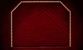 Movie still from “Princes and Princesses” (2000), directed by Michel Ocelot – A red stage with lights on the wall; Wide shot, Overhead angle