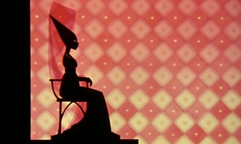 Movie still from “Princes and Princesses” (2000), directed by Michel Ocelot – A silhouette of a woman sitting on a chair; Wide shot, Low angle