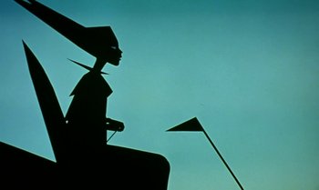 Movie still from “Princes and Princesses” (2000), directed by Michel Ocelot – A silhouette of a person sitting on top of a pole; Medium shot, Low angle