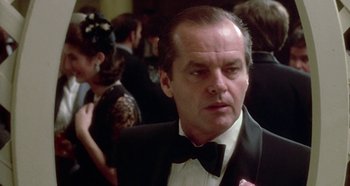 Movie still from “Prizzi's Honor” (1985), directed by John Huston – A man in a suit and bow tie in front of a crowd; Close Up shot, Over the shoulder angle