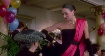 Movie still from “Prizzi's Honor” (1985), directed by John Huston – A woman in a black dress is holding a hat; Medium shot, Over the shoulder angle