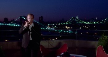 Movie still from “Prizzi's Honor” (1985), directed by John Huston – A man standing in front of a city skyline at night talking on a phone; Wide shot, Low angle
