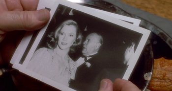 Movie still from “Prizzi's Honor” (1985), directed by John Huston – A person holding an old photo of a man and a woman; Extreme Close Up shot, Over the shoulder angle